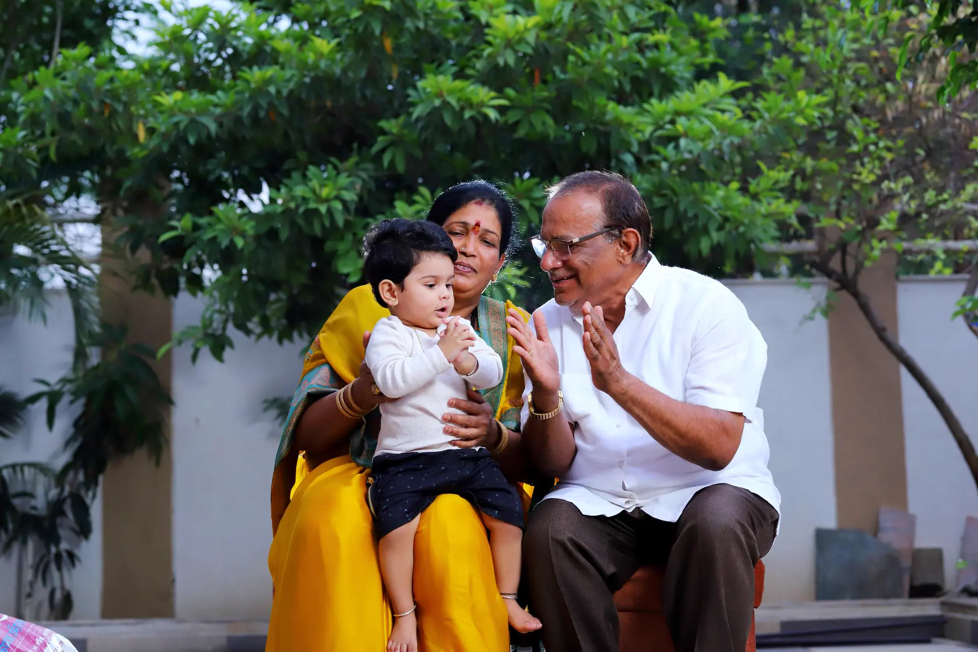 Smiling grandparents playing with their grandchild outdoors