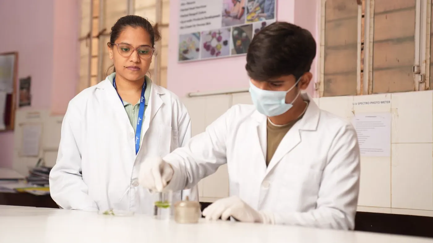 Two laboratory staff in white coats preparing samples at a bench